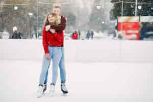 Free photo cute couple in a red sweaters having fun in a ice arena