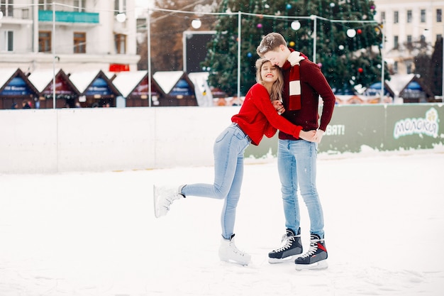 Cute couple in a red sweaters having fun in a ice arena