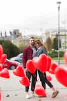 Free photo cute couple surrounded by heart balloons