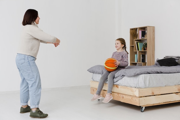 Cute daughter holding basketball indoors