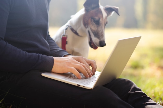 Free Photo cute dog with owner and laptop in park