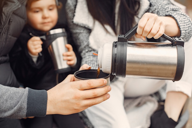 Cute family taking a hot drink in a winter field