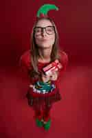 Free photo cute female nerd with small gift dressed in christmas clothes