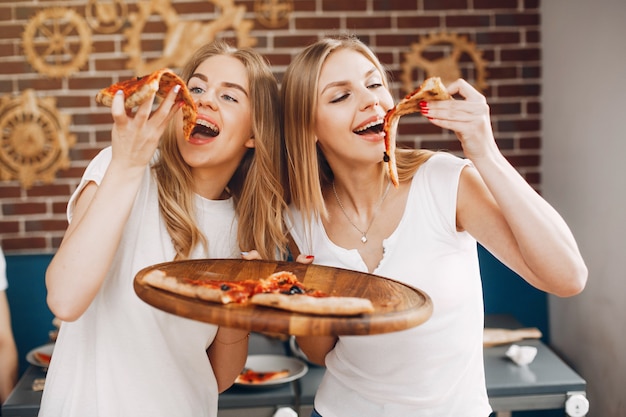 Free photo cute friends in a cafe eatting a pizza