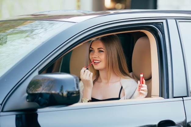 Cute  girl applying lipstick in a car