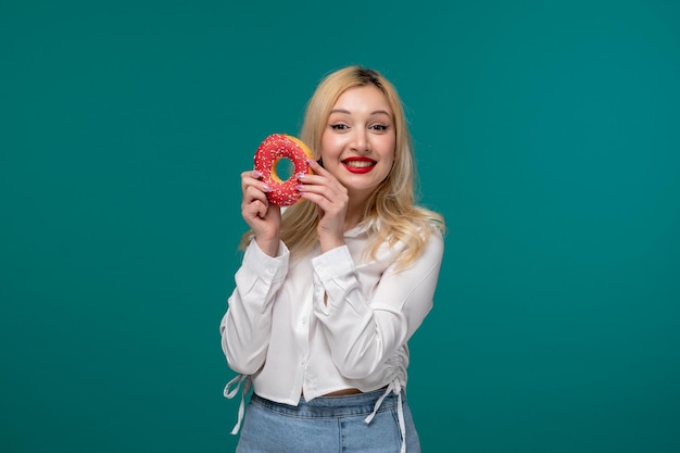 Cute girl blonde beautiful young girl in a white neat shirt excited holding pink donut