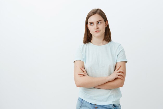 Cute girl bothered with unpopular clingy guy trying ask her out looking irritated and annoyed left crossing hands on chest and pursing lips being indifferent and uninterested posing over white wall