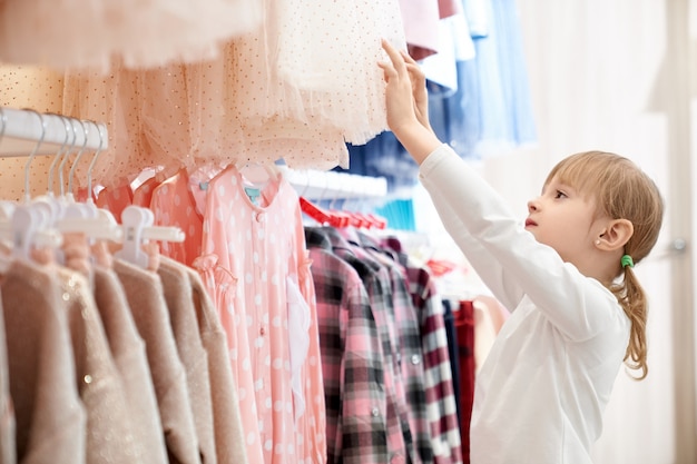 Free photo cute girl choosing modern, stylish children clothing.