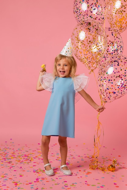 Free photo cute girl in costume with balloons and party hat