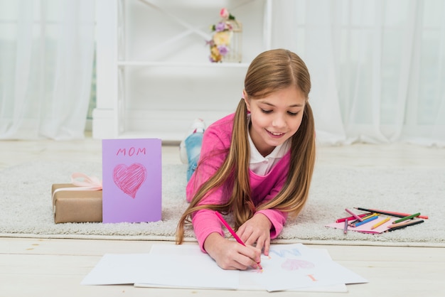 Free photo cute girl drawing on paper near greeting card