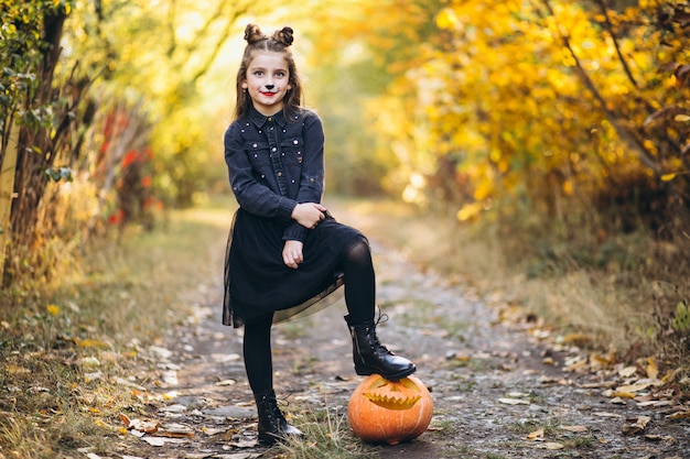 Free Photo cute girl dressed in halloween costume outdoors with pumpkins