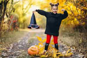 Free photo cute girl dressed in halloween costume outdoors with pumpkins