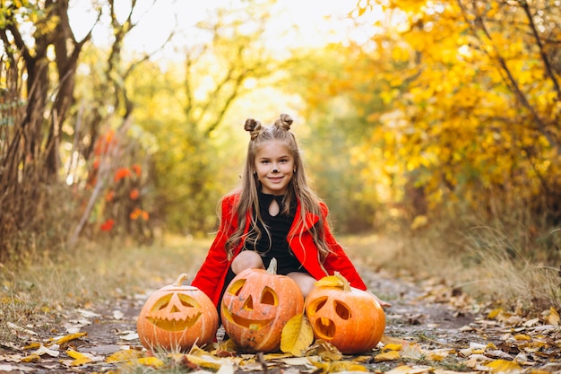 Free photo cute girl dressed in halloween costume outdoors with pumpkins