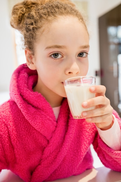 Free photo cute girl drinking milk in kitchen