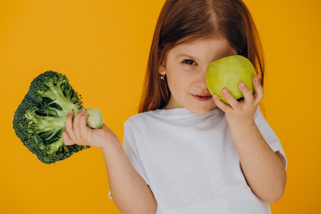 Cute girl holding broccoli and apple