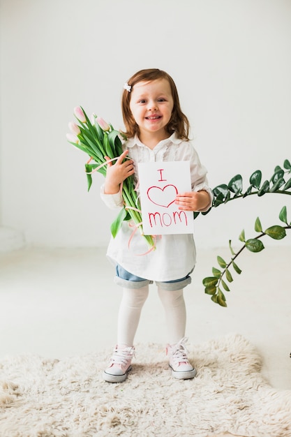 Free photo cute girl holding greeting card with i love mom inscription