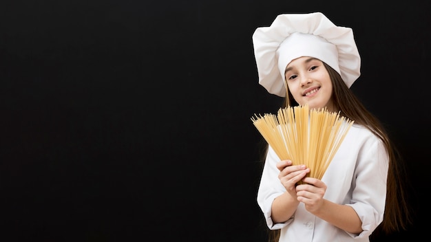 Free photo cute girl holding raw spaghetti