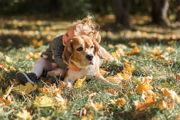 Free Photo cute girl hugging her pet in grass