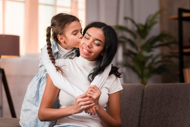 Cute girl kissing her mom on cheek