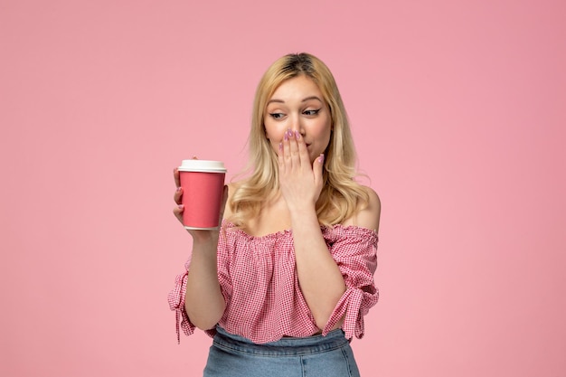 Cute girl lovely young lady with red lipstick in pink blouse covering mouth with pink cup