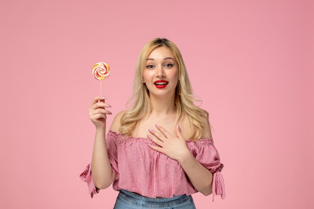 Cute girl lovely young lady with red lipstick in pink blouse standing with lollipop and smiling