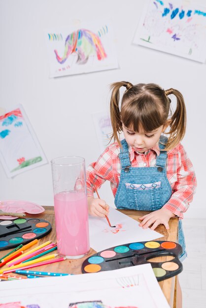 Cute girl painting with aquarelle on paper