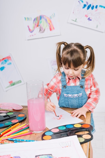 Cute girl painting with aquarelle on paper