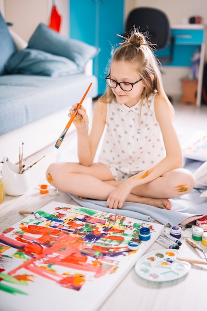 Cute girl painting with gouache on floor