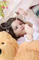 Free photo cute girl playing with light bulbs from bed