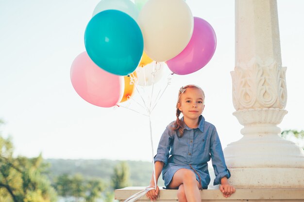 Cute girl portrait holding colorful balloons in the city park