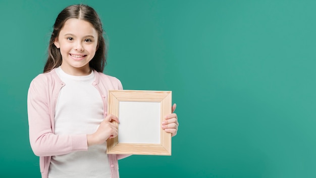 Cute girl posing with photo frame in studio