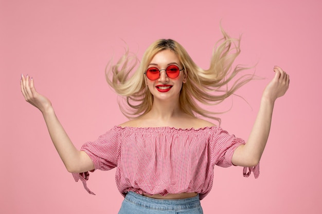 Cute girl pretty blonde lady wearing red glasses in pink shirt throwing hair in the air flipping