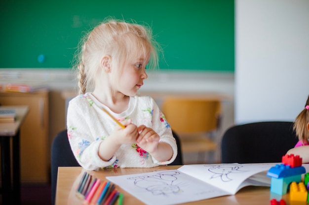 Cute girl sitting at table in classroom