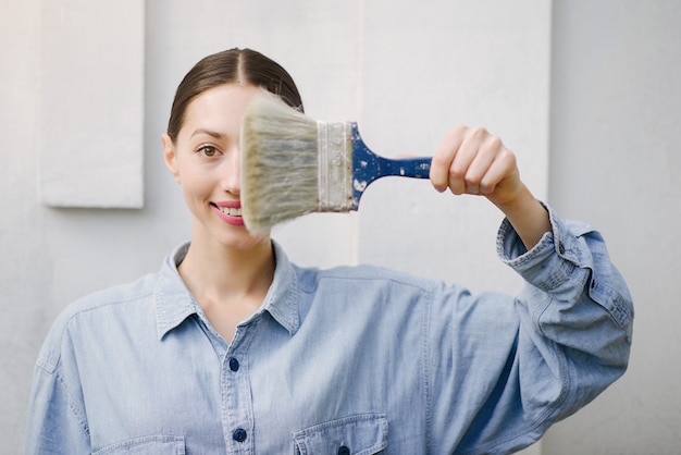 Free photo cute girl standing near wall with repair tools