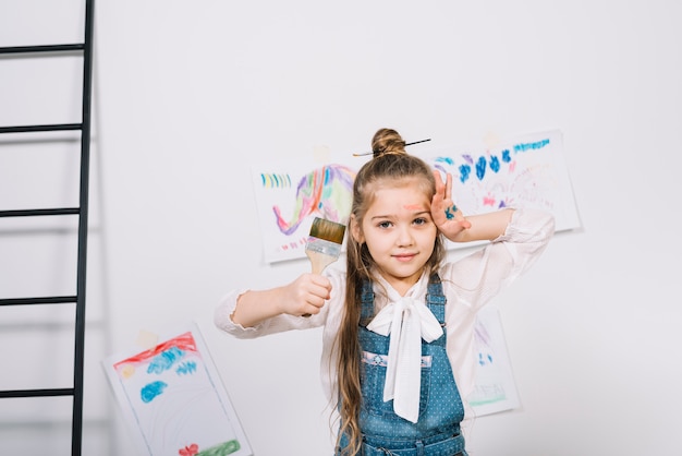 Free photo cute girl standing with brush near drawings