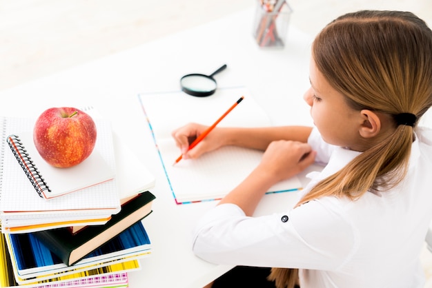 Free photo cute girl in uniform studying at desk