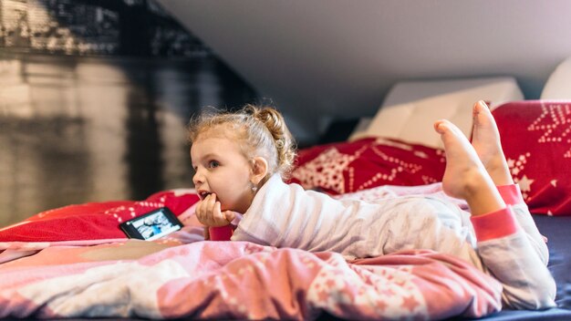 Cute girl watching video on bed