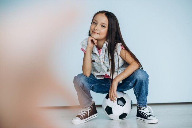 Cute girl with football ball at studio