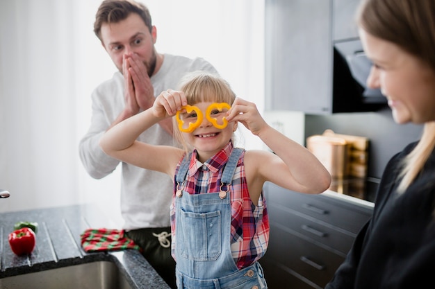 Cute girl with pepper cooking with parents