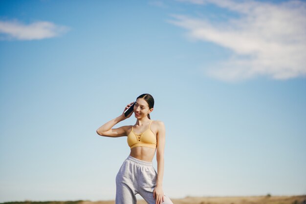 Cute girl with phone training on blue sky