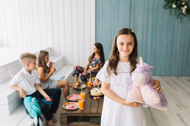 Cute girl with toy unicorn on birthday party