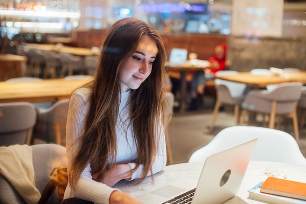 Free Photo cute girl works on laptop in hipster cafe