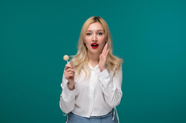 Cute girl young adorable pretty girl in a white neat shirt calling someone holding candy