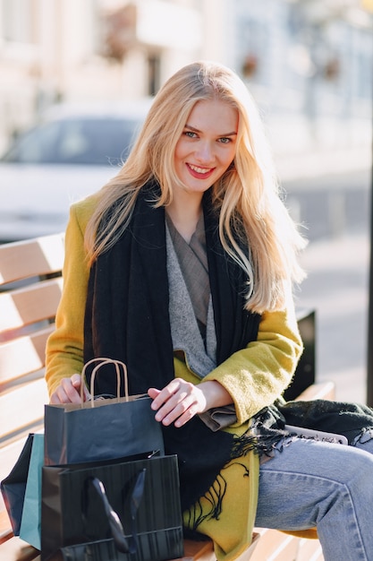 Cute happy attractive blonde woman with packages on the street in sunny warm weather