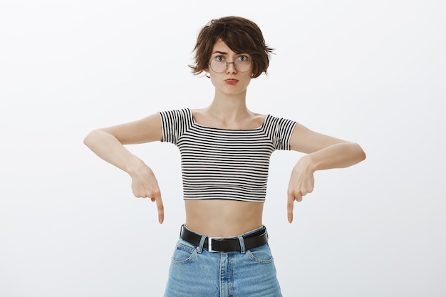 Free photo cute hipster girl in cropped top pointing fingers down