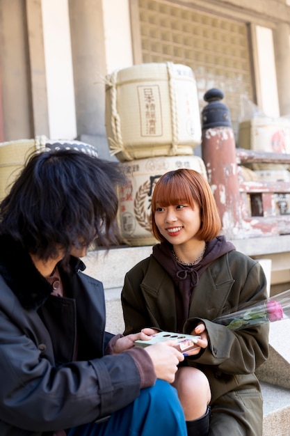 Free photo cute japanese couple exchanging white day gift outdoors