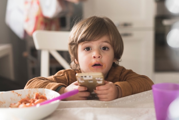 Cute kid holding phone at table