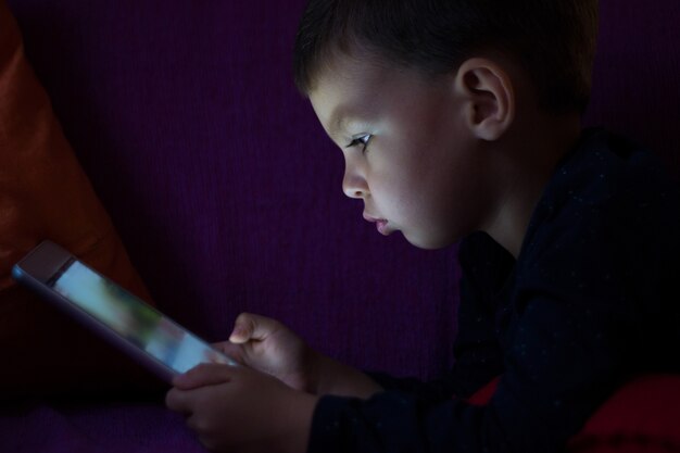 Cute kid with tablet in the dark