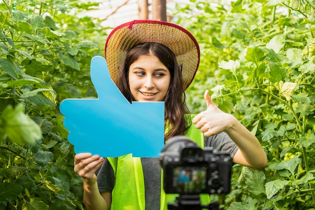 Cute lady holding thumb up sign at the green house