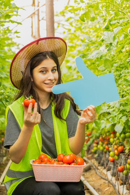 Cute lady holding tomato and idea board the greenhouse